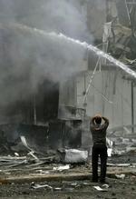 Ebn mand betragter de brændene bygninger efter angrebet, der kostede fire mennesker livet. - Foto: AP 
