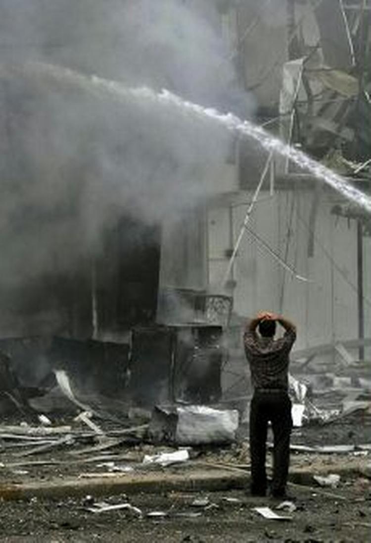 Ebn mand betragter de brændene bygninger efter angrebet, der kostede fire mennesker livet. - Foto: AP 