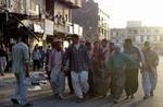 En gruppe irakere bærer et lig væk fra det marked i Tikrit, hvor mindst 33 mistede livet og 70 blev såret. - Foto: AP 