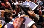 Medlemmer af protestbevægelsen Kifaya (Nok) river billeder af præsident Hosni Mubarak i stykker. - Foto: AP 