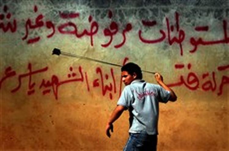 Palæstinensisk aktivist bruger stenslynge mod israelske politifolk under et nyligt sammenstød nær Ramallah. To israelske soldater hævder, at de fik ordre til at udføre et angreb på palæstinensiske politifolk som 