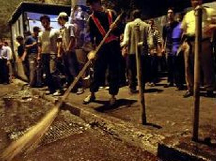 En gadefejer gør rent efter bomben i Teheran. - Foto: AP 