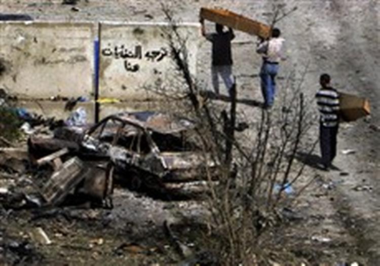 20. juni 2005. En kiste bæres gennem haven på en politistation i Bagdad. Oprørere angreb med tre bil8bomber, mindre håndvåben og raketdrevne granater. Mindst 8 politifolk og en baby blev dræbt.   Foto: AP/Khalid Mohamm 