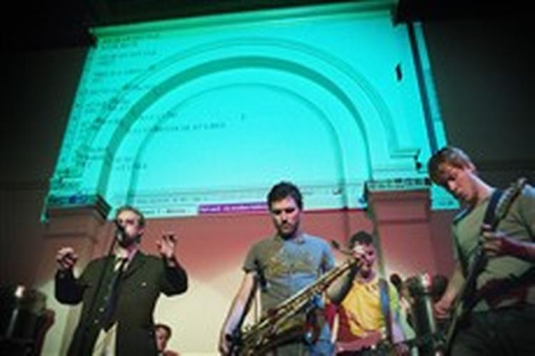 Mike H blander jazz og poesi, men lade sig gerne udfordre på teksterne af en anerkendt lyriker. Mens han synger fra scenen, bliver den alternative tekst smækket op på væggen bagved.   Foto: Morten Langkilde 