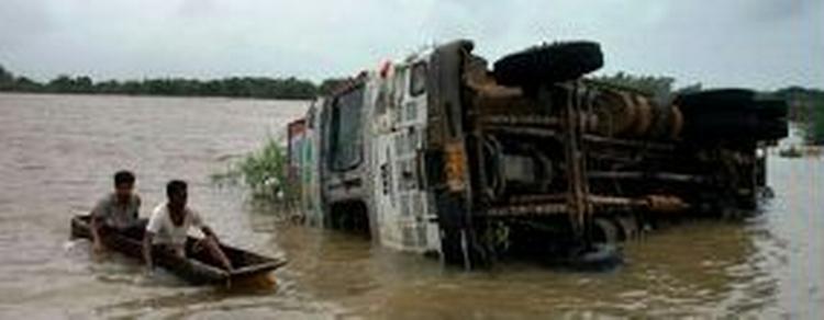 To personer passerer en væltet bus i Gujarat i Indien. - Foto: AP 