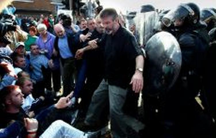 Sinn Fein-leder Gerry Adams kommer i klemme mellem irske nationalister, der protesterer, og politiet. - Foto: AP 