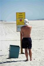 En strandgæst studerer advarselsskiltet ved pigtrådshegnet på stranden på Skallingen.   Foto: Rasmus Baaner 