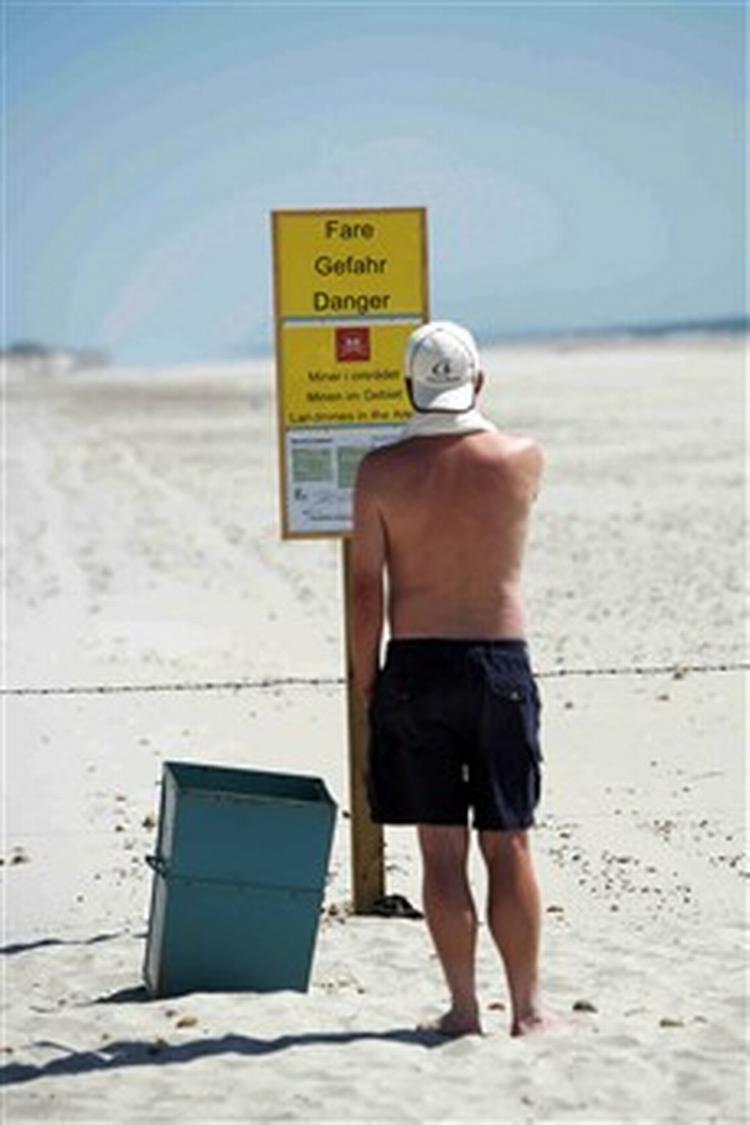 En strandgæst studerer advarselsskiltet ved pigtrådshegnet på stranden på Skallingen.   Foto: Rasmus Baaner 