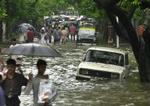 Folk vader gennem en oversvømmet gade i Mumbai, hvor regnen i dag atter er taget til. - Foto: AP 