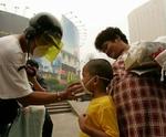 En far giver sin søn luftmaske på i Kuala Lumpur, der er dækket af tåge. - Foto: AP 