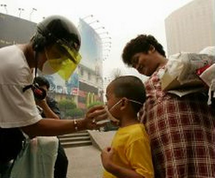 En far giver sin søn luftmaske på i Kuala Lumpur, der er dækket af tåge. - Foto: AP 