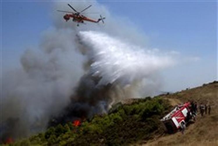 Brandfolk forsøger at slukke ilden i et Boeing 737-fly, der styrtede ned nord for Athen og dræbte alle 121 mennesker om bord.   Foto: AP 