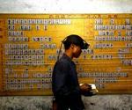 En redningsmedarbejder passerer forbi listen over de minearbejdere fra Daxing-minen i Guangdongprovinsen i Kina. 123 af dem er stadig savnet og formodes druknet.   Foto: Liu Dawei/AP 