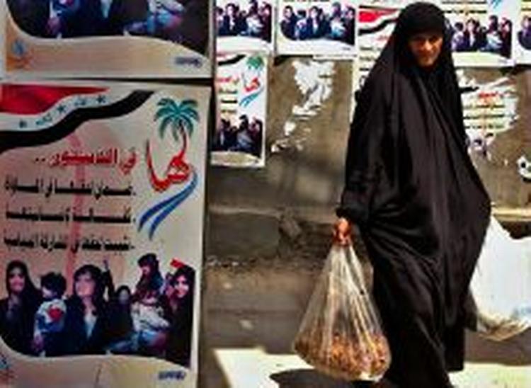 En kvinde i Basra i Irak passerer en plakat, som omtaler kvinders rettigheder i den nye forfatning. - Foto: AP 