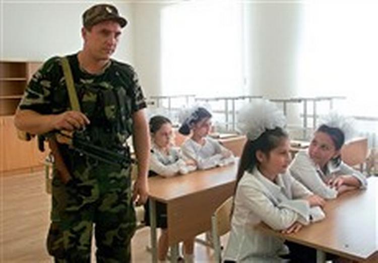Sikkerheden er skærpet på alle Ruslands skoler, der i dag begynder efter sommerferien. En politimand holdt godt øje med de små piger, da de i går prøvesad stolene i deres nye skole i Grosnij.   Foto: Artur Magomadov, 