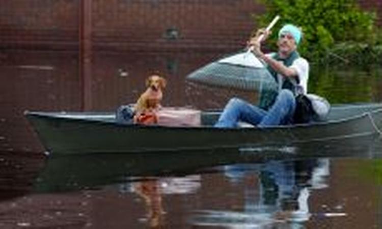 En mand med en rive padler sig selv og hunden i sikkerhed i New Orleans. - Foto: AP 