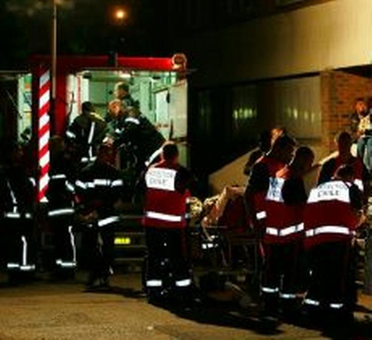 Brandfolk samles uden for den udbrændte bygning i Paris-forstaden. - Foto: AP 