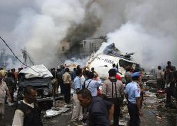Redningsfolk forsøger at redde overlevende fra flystyrtet på Sumatra. 16 overlevede flystyrtet i et beboelseskvarter. - Foto: AP 