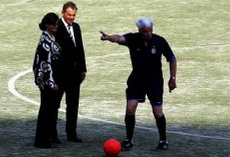 Den britiske premierminister ønsker mere kinesisk fokus på menneskerettigheder. Men Blair havde selv svært ved at fokusere på bolden, da han besøgte en kinesisk fodboldskole. Dommeren er Sir Bobby Robson. - Foto: AP 