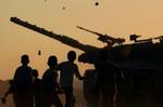Unge palæstinensere kaster sten mod en israelsk tank ved bosættelsen Neve Dekalim i Gaza. Senere blev det til kampe, hvor en palæstinenser blev dræbt. - Foto: AP 