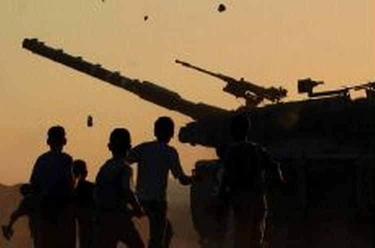 Unge palæstinensere kaster sten mod en israelsk tank ved bosættelsen Neve Dekalim i Gaza. Senere blev det til kampe, hvor en palæstinenser blev dræbt. - Foto: AP 