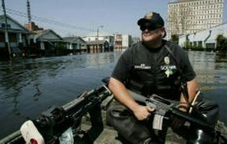 Bevæbnede politifolk patruljerer i de oversvømmede gader i New Orleans. - Foto: AP 