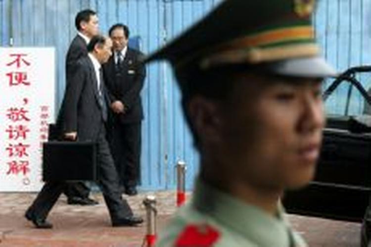 Den japanske delegation haster forbi kinesiske vagter til forhandlinger i Beijing om Nordkorea atomprogram i dag. - Foto: AP 