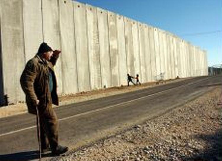 En palæstinenser ser på legende børn ved Israels sikkerhedsmur på Vestbredden. Israels Højesteret har bestemt at muren ikke må følge den oprindelige linjelægning. - Arkivfoto: AP 