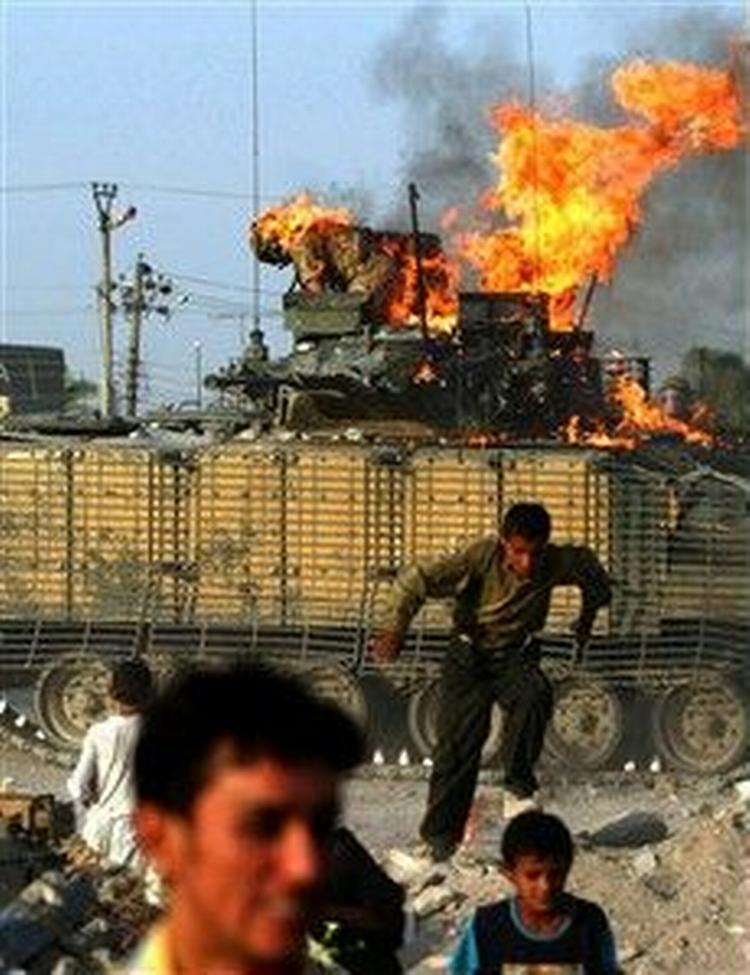 En britisk soldat med ild i tøjet forsøger at redde sig ud af en brændende kampvogn i Basra i det sydlige Irak. - Foto: AP 
