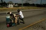 En mand bruger en indkøbsvogn til at transportere de ejendele, han redede med sig, da han blev evakueret fra New Orleans. Som mange andre vender han hjem på ny. - Foto: AP 