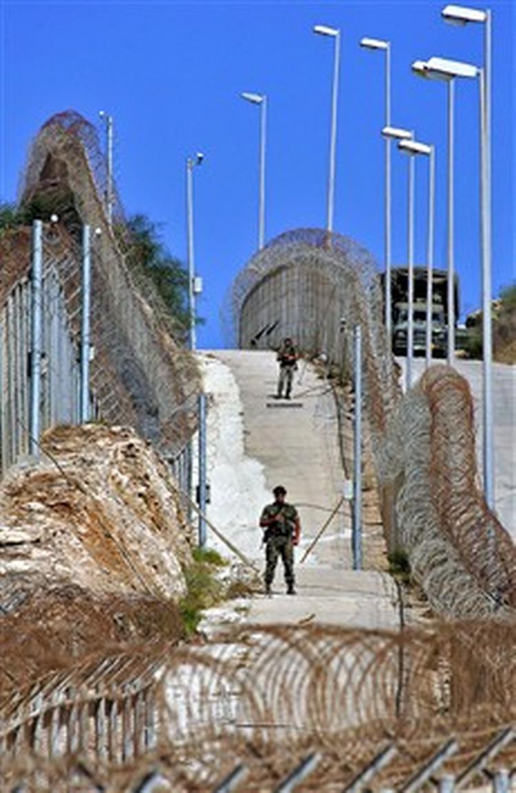 Spanske soldater mellem de hegn, der ikke har kunnet holde afrikanske flygtninge ude.   Foto: AP 