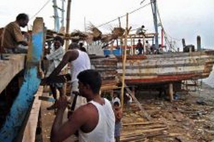 Arbejdere reparerer en ødelagt båd i Nagappattinam, den indiske region, som blev hårdest ramt af tsunamien. Sådanne naturkatastrofer driver millioner på flugt. - Foto: AP 