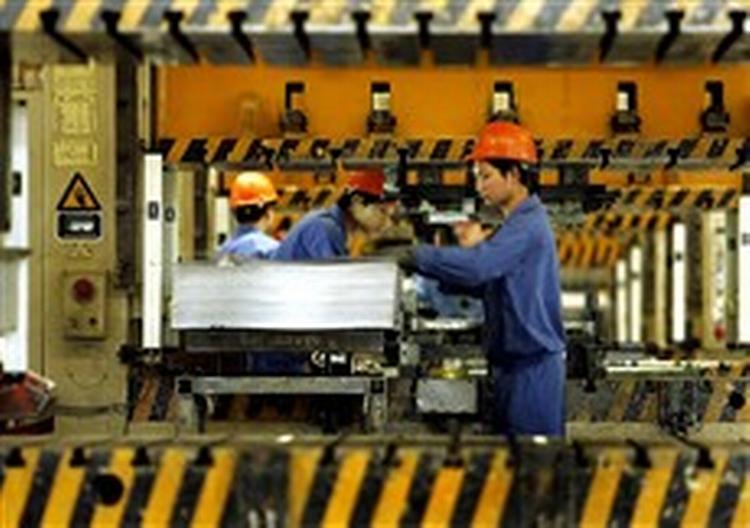 Kinesiske arbejdere forarbejder stål, der skal bruges til bildele på en fabrik i Ningbo. Fabrikken er i gang med at udvide produktionen som følge af Kinas økonomiske vækst.   Foto: Eugene Hoshiko 