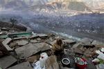 En pakistansk kvinde forsøger at holde varmen ved hjælp af en balje varmt vand, mens hun håber på nødhjælpsforsyninger.   Foto: AP 