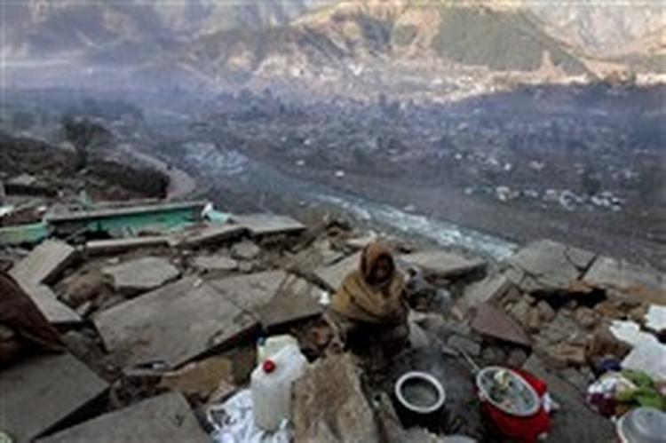 En pakistansk kvinde forsøger at holde varmen ved hjælp af en balje varmt vand, mens hun håber på nødhjælpsforsyninger.   Foto: AP 