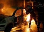 En brandmand forsøger at slukke en brændende bil under optøjerne i nat. - Foto: AP 