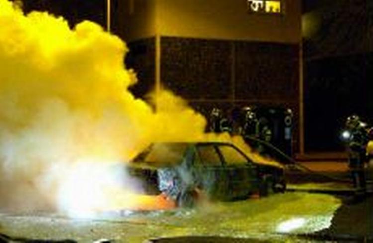 Politiet forsøger at slukke en brand i en bil i Venissieux i Lyon i nat. - Foto: AP 