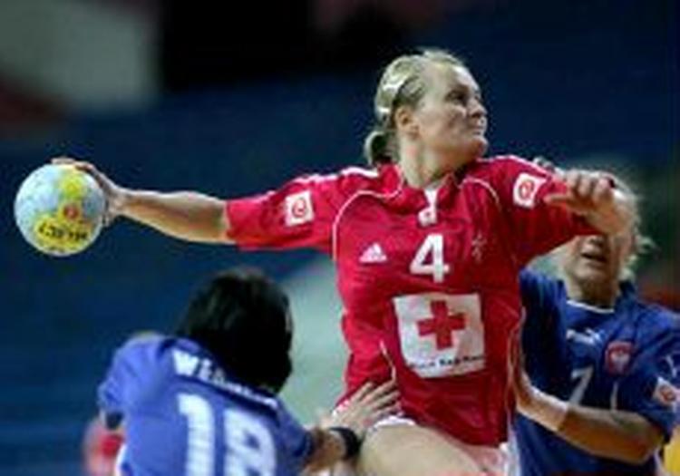 Rikke Nielsen med Røde Kors på maven i færd med et skud under VM. Logoet skaber forvirring blandt håndboldtilhængere der tror, at hjælpeorganisationen selv har betalt for reklamepladsen. - Foto: Lars Poulsen 