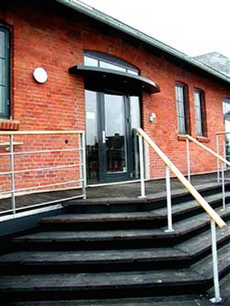 .Hovedindgangen til Pakhuset i Odder. Det var på et gelænder magen til det til venstre, at den unge mand på forunderlig vis fik viklet sig så voldsomt ind, at han ikke selv kunne vikle sig ud igen.   Foto: Pakhuset-odder.dk 