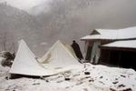 En mand forsøger at rejse familiens telt op i Awan Patti i Jhelum dalen i Kashmir. Jordskælvsområdet oplevede i dag de heftigste regn- og snefald hidtil i denne pakistanske vinter. - Foto: AP 