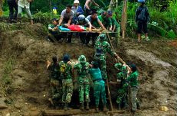 Indonesiske redningsfolk hjælper en ældre kvinde ved Panti i den østlige del af Java efter det voldsomme uvejr, som har forårsaget jordskred og isolation af landsbyer. - Foto: AP 