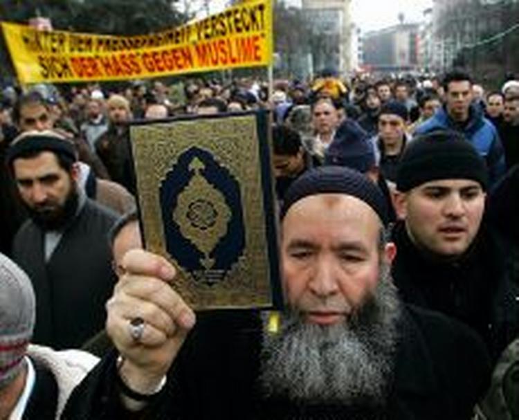 En demonstrant holder Koranen op under protester mod Muhammedtegningerne i dag i Düsseldorf. - Foto: AP 