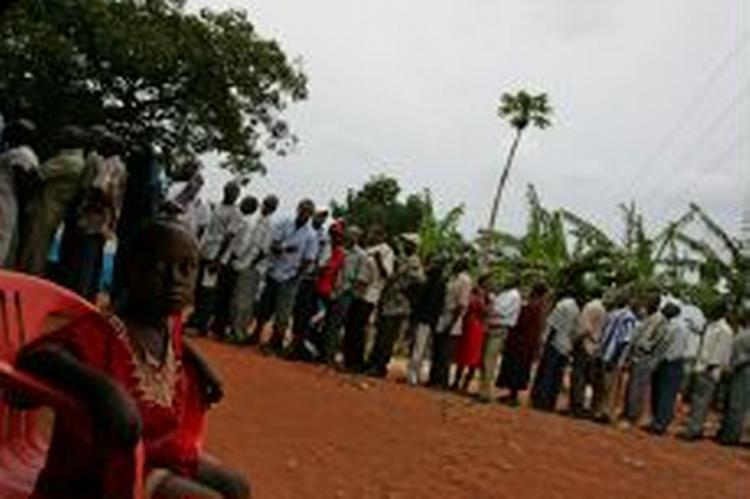 En ugandisk dreng venter på faderen, der står i kø for at stemme ved et valglokale i Ugandas hovedstad Kampala. - Foto: AP 