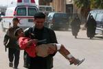 En irakisk mand bærer en såret dreng væk efter en af de eksplosioner, der i dag ramte Bagdad. - Foto: AP 