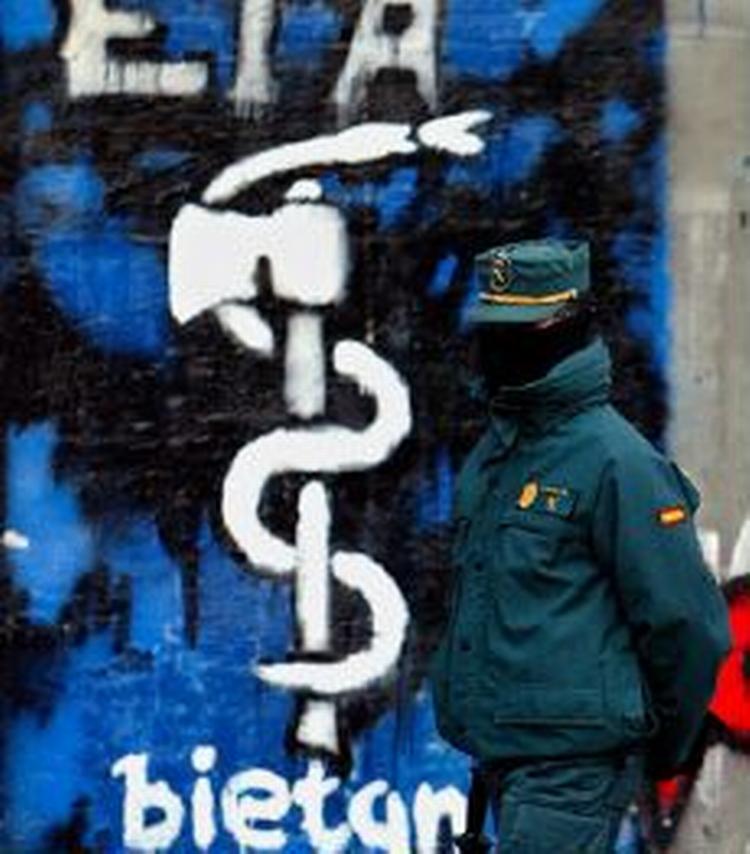 En maskeret vagt går forbi ETA-graffiti i Baskerlandet i det nordlige Spanien. - Arkivfoto: AP 
