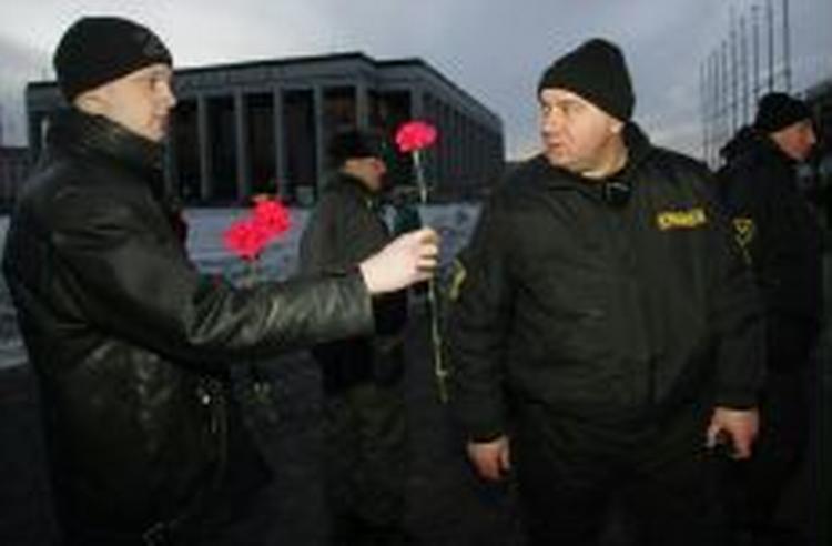 En demonstrant giver blomster til politiet ved Oktoberpladsen i Minsk. I dag brød demonstranter gennem politiets afspærringer. - Foto: AP 
