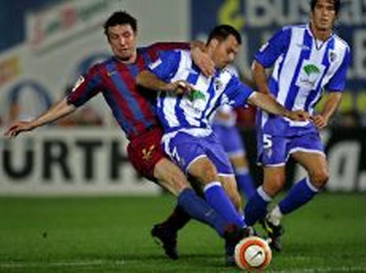 Malagas Gerardo tackles af Barcelonas Marc van Bommel i en kedelig kamp i feriebyen. Med 0-0 bevarer Malaga håbet om at undgå nedrykning. - Foto: AP 