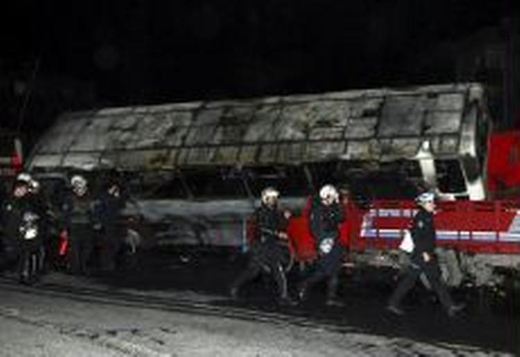 Tyrkiske brandmænd ved den udbrændte bus, der dræbte tre personer, da den kørte over dem. - Foto: AP 