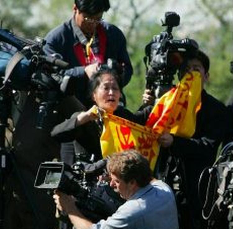 Den protesterende kvinde viftede med et flag med de røde og gule farver, symboliserende Falun Gong.- Foto: AP 