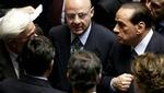 Berlusconi (th.) diskuterer med andre parlamentarikere før afstemningen. - Foto: AP 